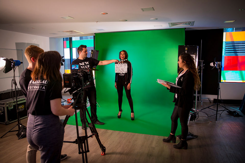 students filming girl in front of green screen