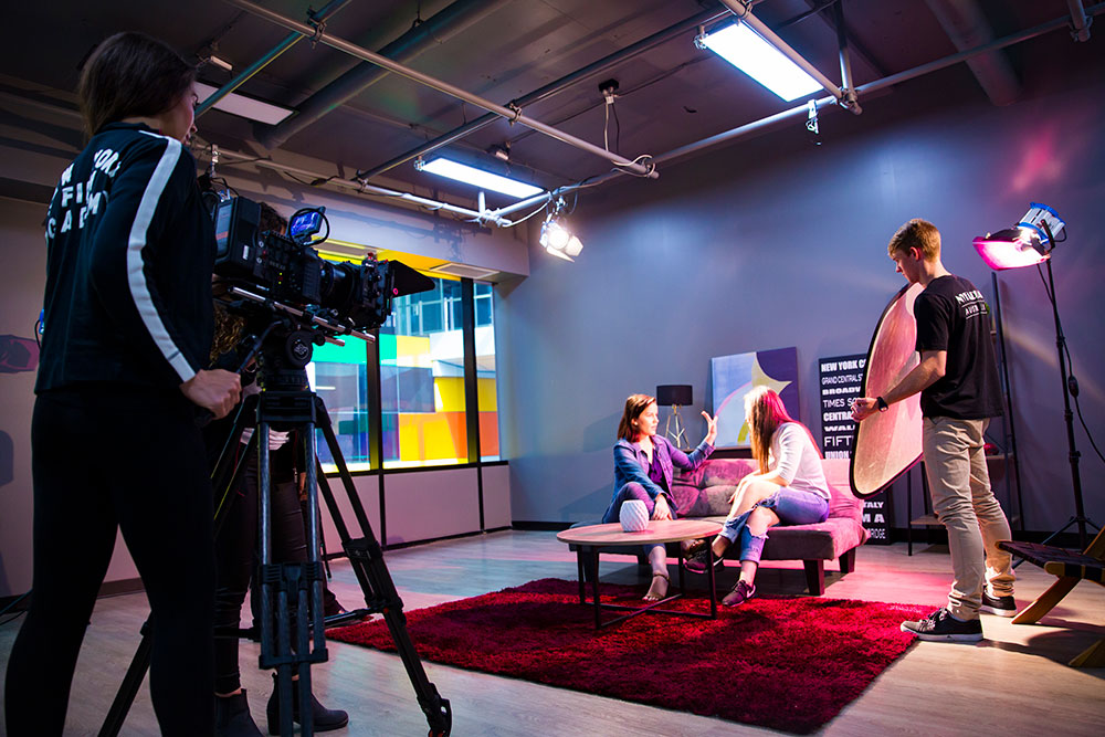 two students on couch filming scene