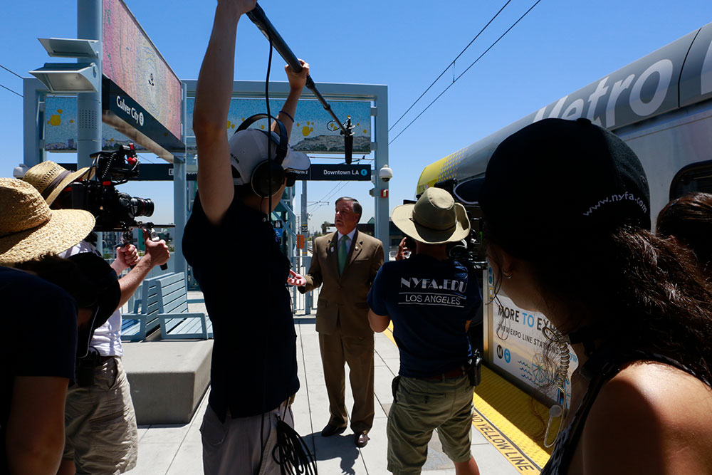 group filming man in front of metro rail in downtown la